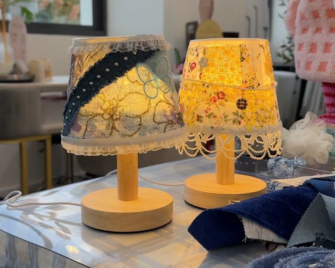 Two small table lamps with lace shades on a checkered tablecloth.